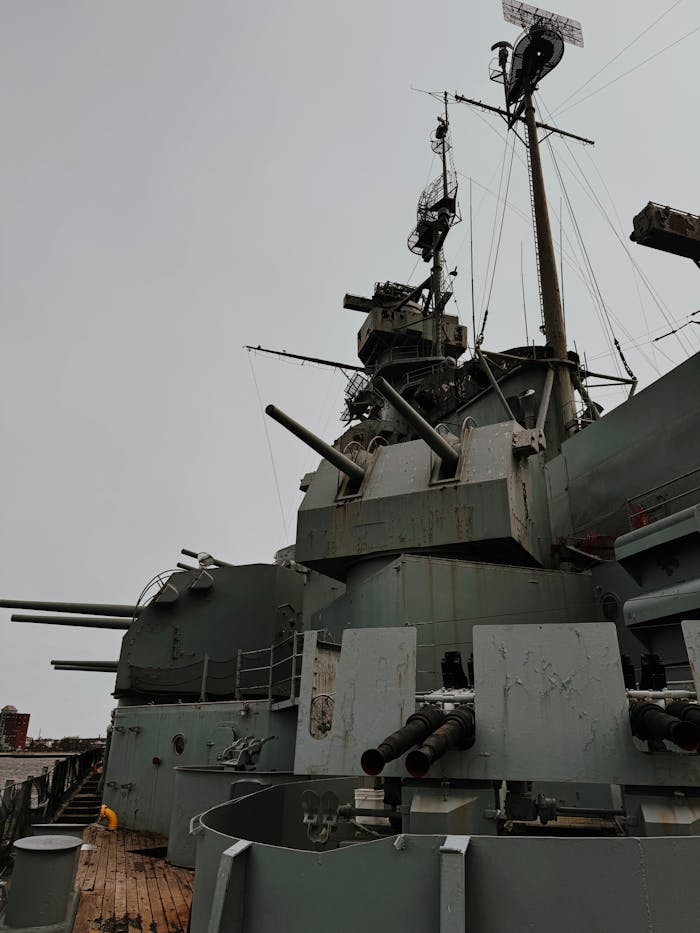 services-04 Close-up of a battleship's gun turrets and radar systems on a cloudy day.