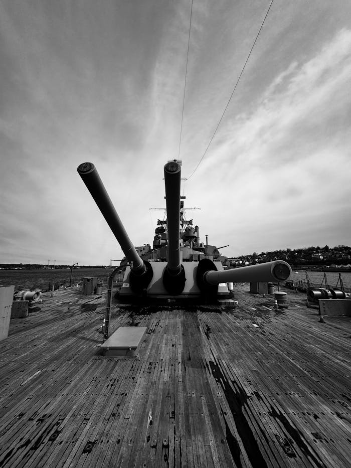 about-us-01 Dramatic black and white photo of USS Alabama battleship showcasing its powerful cannons.