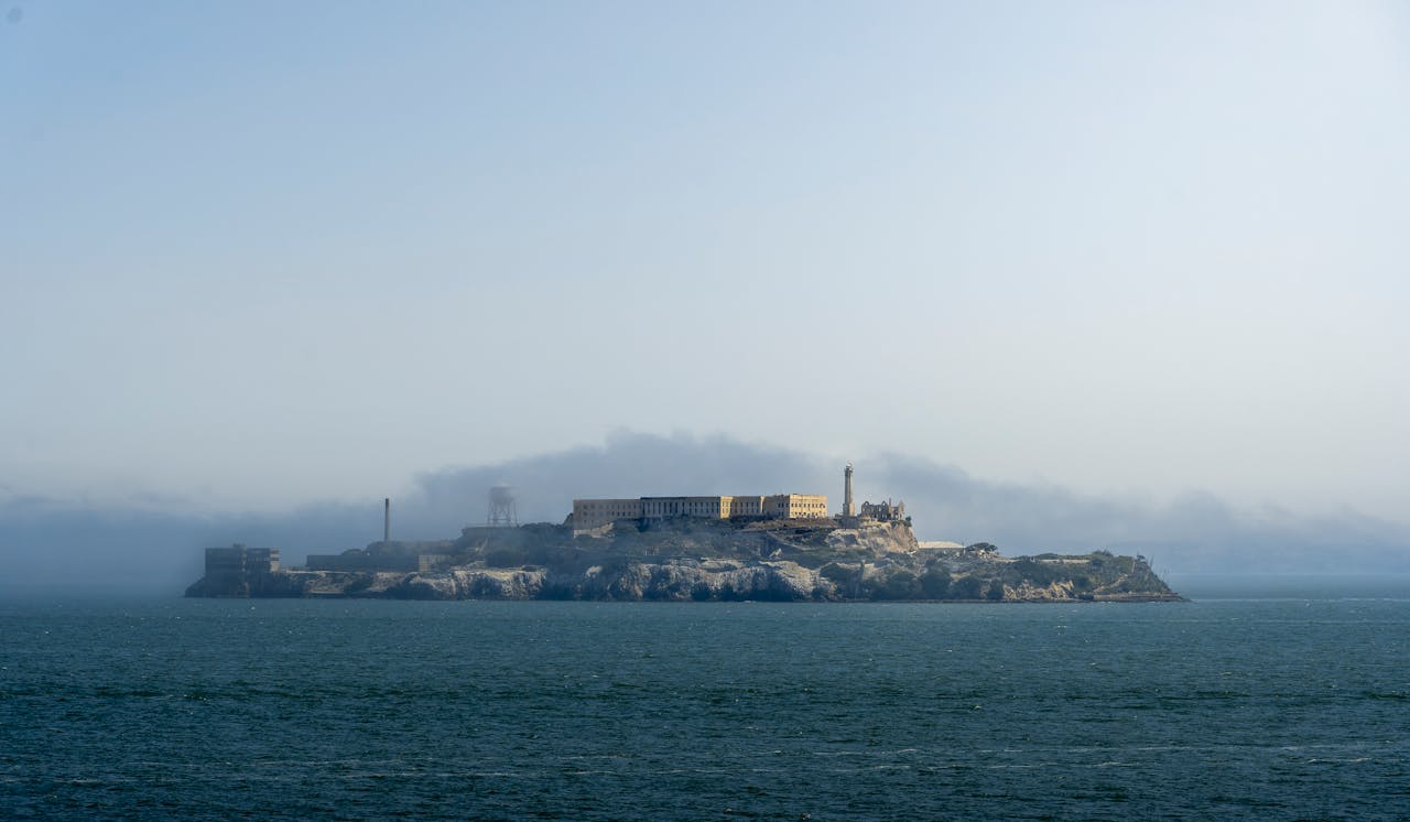 services-03 A serene view of Alcatraz Island silhouetted against a cloudy sky in San Francisco Bay.